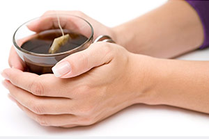 Female hands holding onto a cup of tea.