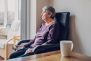 An elderly woman in a home suffering from financial abuse is staring out the window. An elderly woman in a home suffering from financial abuse is staring out the window.